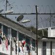 Inmates extend their hands at the Modelo prison in Bogota after a riot on March 22 left 23 prisoners dead and 90 wounded
