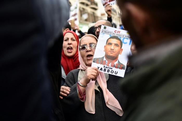 People march with signs calling for the release of detained Algerian opposition figure Karim Tabbou on January 24, 2020, during the 49th consecutive Friday demonstration against the Algerian government and the ruling class in Algiers