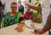Hon. Brenda Bii, CEC Health Kericho County, has her blood pressure and body temperature checked during a walkthrough of the medical camp held by M-PESA Foundation at Kapcheluch Primary School, Kericho County.