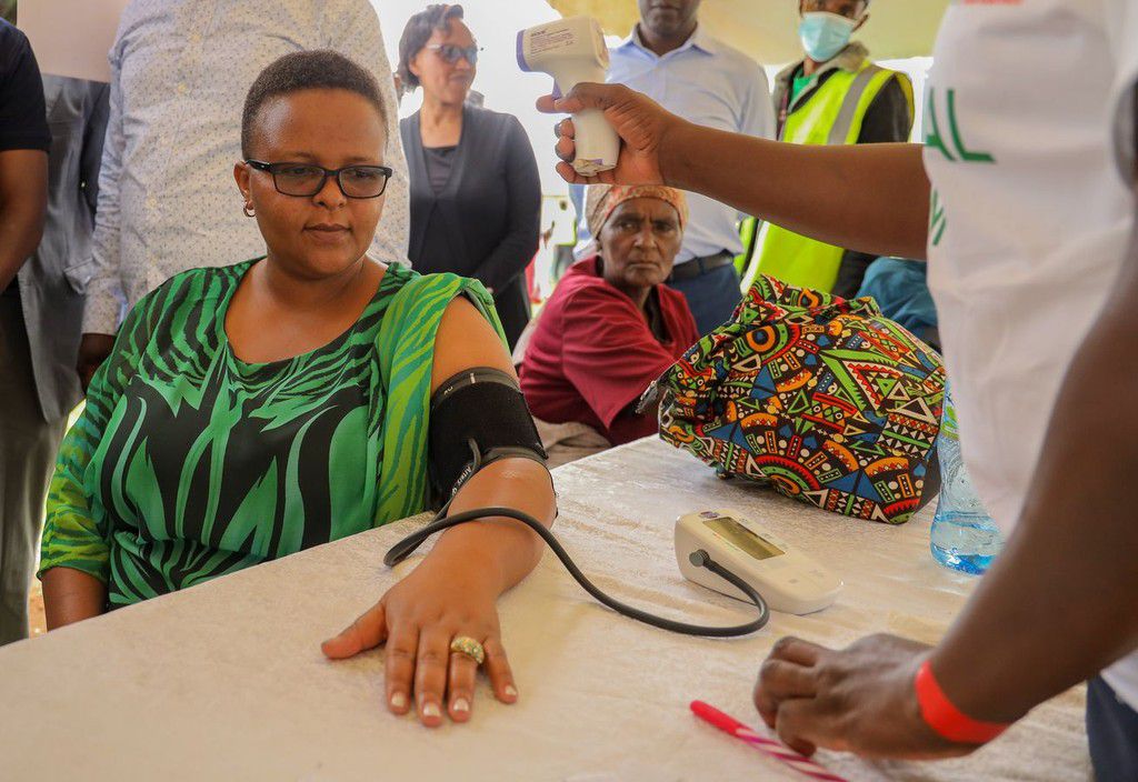 Hon. Brenda Bii, CEC Health Kericho County, has her blood pressure and body temperature checked during a walkthrough of the medical camp held by M-PESA Foundation at Kapcheluch Primary School, Kericho County.