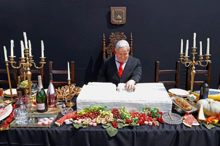 A doll depicting Israeli Prime Minister Benjamin Netanyahu sits at a table simulating the "Last Supper" during a protest performance by Israeli artist Itay Zalait on July 29, 2020 at Rabin Square in Tel Aviv
