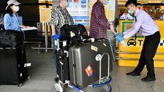 A worker sprays sprays hand sanitizer onto passengers arriving in March 2020 at Taoyuan Airport in Taiwan, one of the few places for which the United States has completely lifted its warning to avoid travel due to the coronavirus