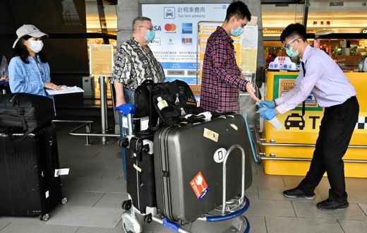 A worker sprays sprays hand sanitizer onto passengers arriving in March 2020 at Taoyuan Airport in Taiwan, one of the few places for which the United States has completely lifted its warning to avoid travel due to the coronavirus