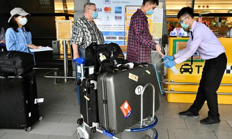 A worker sprays sprays hand sanitizer onto passengers arriving in March 2020 at Taoyuan Airport in Taiwan, one of the few places for which the United States has completely lifted its warning to avoid travel due to the coronavirus