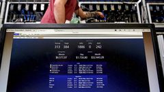 A bitcoin-mining computer and a screen showing bitcoin exchange rates at Bitminer Factory in Florence, Italy.
