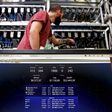 A bitcoin-mining computer and a screen showing bitcoin exchange rates at Bitminer Factory in Florence, Italy.