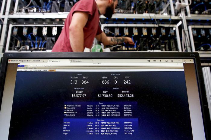 A bitcoin-mining computer and a screen showing bitcoin exchange rates at Bitminer Factory in Florence, Italy.