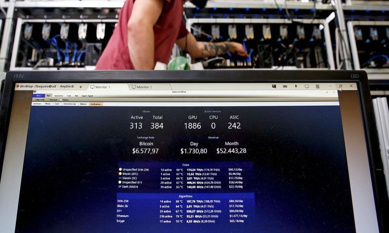 A bitcoin-mining computer and a screen showing bitcoin exchange rates at Bitminer Factory in Florence, Italy.