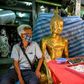 A vendor wearing a face mask against the spread of the coronavirus sits beside a Buddha statue as he waits for customers at an amulet market in Bangkok