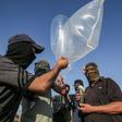 Palestinian militants attach a fire bomb to inflated plastic bags and condoms before launching it across the Gaza border into Israel