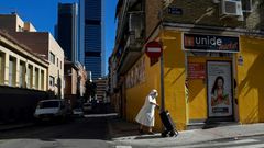 A nun wearing a facemask pushes a trolley in the outskirts of Madrid with the Cuatro Torres business area in the background