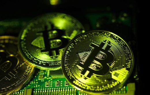 Visual representations of digital cryptocurrency Bitcoin (BTC) are arranged on a circuit board