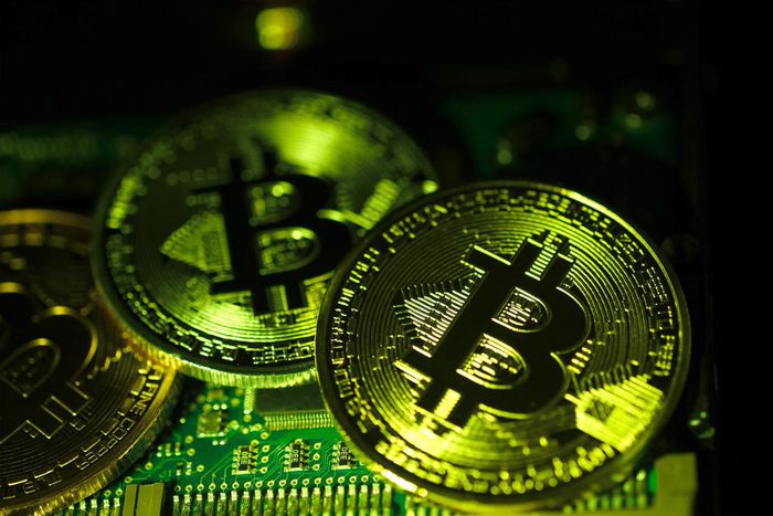 Visual representations of digital cryptocurrency Bitcoin (BTC) are arranged on a circuit board