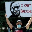 A demonstrator holds up a poster with a rendition of George Floyd on May 30 in Denver