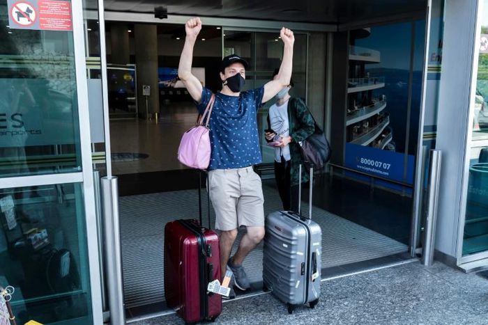 A traveller, mask-clad due to the COVID-19 coronavirus pandemic, arriving on one of the first flights from Britain gestures as he walks with luggage out of the terminal at Cyprus' Larnaca International Airport on August 1