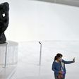 A visitor -- wearing a face mask -- takes a selfie at the Soumaya Museum in Mexico City in front of a Rodin sculpture