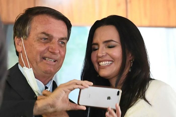 Analysts say the downturn has been mitigated by a stimulus package decided on by the government of Brazilian President Jair Bolsonaro, shown here posing with a doctor before the event "Brazil beating COVID-19" at Planalto Palace on August 24, 2020