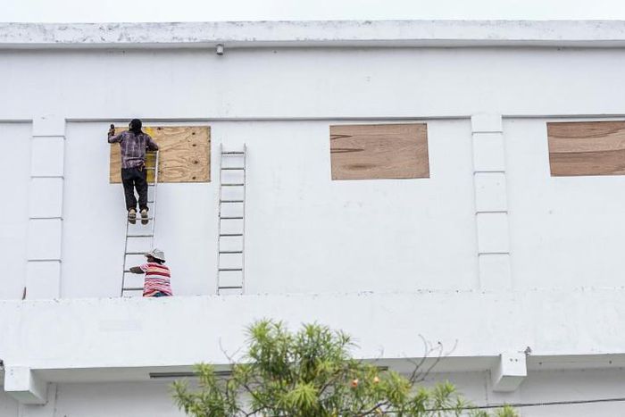 Workers board up the windows of a store in preparation for hurricane Nana in Belize City on Wednesday