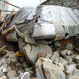 A villager inspects a damaged car among the debris of houses after a flash flood hit Charikar