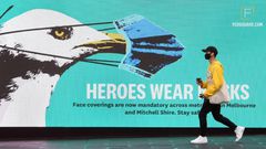 A man walks past a sign urging people to wear face masks in Melbourne as the city battles an outbreak of coronavirus