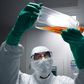A lab technician in Personal Protective Equipment (PPE) looks at a reagent bottle before performing vaccine tests at French pharmaceutical giant Sanofi's lab in Val de Reuil