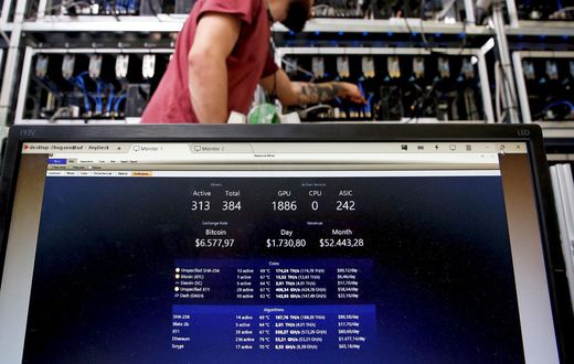 A bitcoin-mining computer and a screen showing bitcoin exchange rates at Bitminer Factory in Florence, Italy.