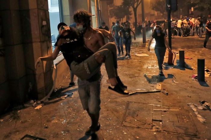 A Lebanese protester carries a wounded demonstrators to safety at the headquarters of the Lebanese association of banks in downtown Beirut on August 8, 2020, following a demonstration against a political leadership they blame for a monster explosion th...