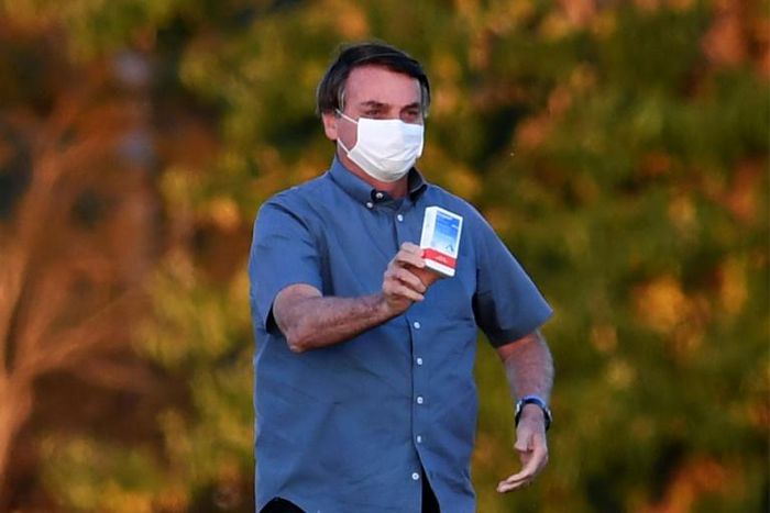 Brazilian President Jair Bolsonaro, seen here showing off a box of hydroxychloroquine to supporters outside presidential palace in Brasilia said nearly everyone will probably get the coronavirus, just like he did