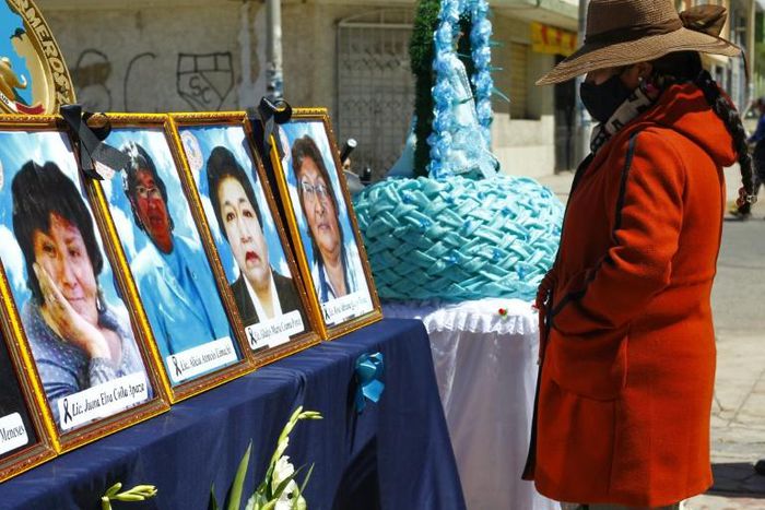 A woman looks at photos of health workers in Puno, Peru who died from Covid-19