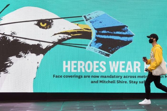 A man walks past a sign urging people to wear face masks in Melbourne as the city battles an outbreak of COVID-19