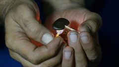 A Pakistani smoker holding a match to a clump of hashish to soften it before mixing it with cigarette tobacco