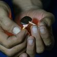 A Pakistani smoker holding a match to a clump of hashish to soften it before mixing it with cigarette tobacco