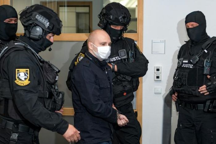 Stephan Balliet (C), who is accused of shooting dead two people after attempting to storm a synagogue in Halle an der Saale, eastern Germany, is escorted to a courtroom at the second day of his trial on July 22, 2020 in Magdeburg, eastern Germany