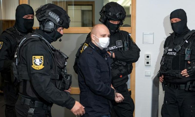 Stephan Balliet (C), who is accused of shooting dead two people after attempting to storm a synagogue in Halle an der Saale, eastern Germany, is escorted to a courtroom at the second day of his trial on July 22, 2020 in Magdeburg, eastern Germany