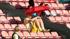 Arsenal's German midfielder Mesut Ozil (C) shelters from the sunshine
