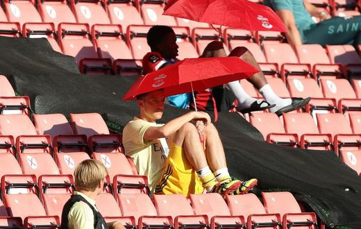 Arsenal's German midfielder Mesut Ozil (C) shelters from the sunshine
