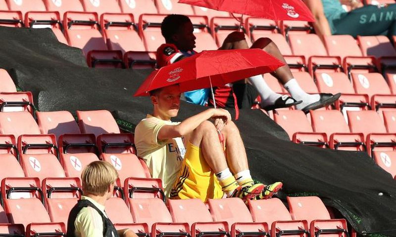 Arsenal's German midfielder Mesut Ozil (C) shelters from the sunshine