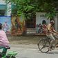 Cyclists ride past the closed gate of a Mumbai movie theatre