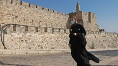A priest, wearing a protective mask amid the Covid-19 pandemic, walks along the walls of Jerusalem's Old City on September 12, 2020