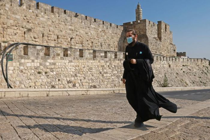 A priest, wearing a protective mask amid the Covid-19 pandemic, walks along the walls of Jerusalem's Old City on September 12, 2020