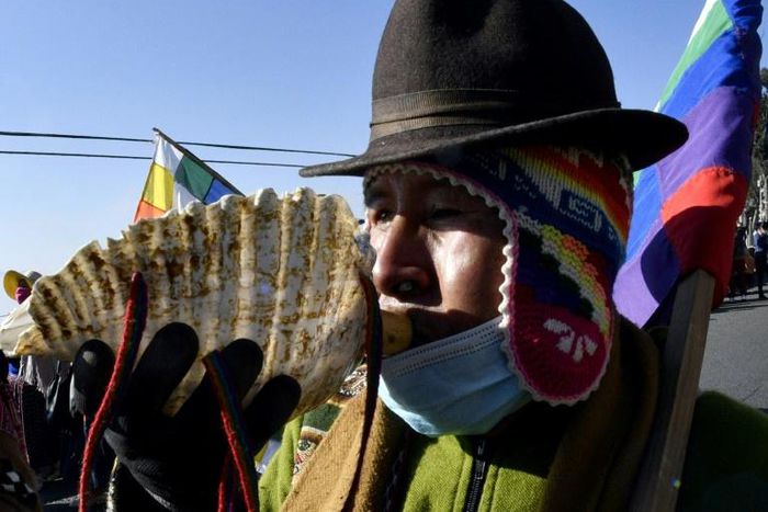 An Amauta, a priest of Bolivia's indigenous Aymara community, blows an instrument during an anti-government march