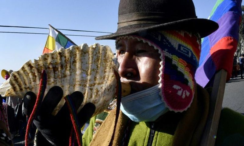 An Amauta, a priest of Bolivia's indigenous Aymara community, blows an instrument during an anti-government march