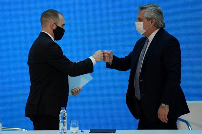 Argentina's President Alberto Fernandez (R) and Economy Minister Martin Guzman greet each other with a fist bump after announcing the restructuring of a $66 billion foreign-law debt