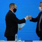 Argentina's President Alberto Fernandez (R) and Economy Minister Martin Guzman greet each other with a fist bump after announcing the restructuring of a $66 billion foreign-law debt