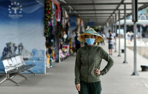 A woman wearing a face mask walks along the Tuan Chau harbour in Ha Long Bay, Vietnam
