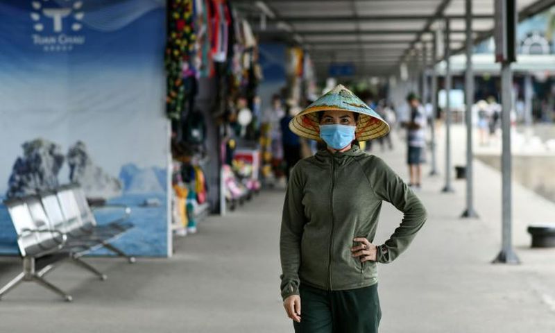 A woman wearing a face mask walks along the Tuan Chau harbour in Ha Long Bay, Vietnam
