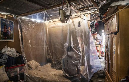 Jonathan, 30, sits on his bed behind a plastic protection as doctors make a round of visits in Ate, on the eastern outskirts of Lima