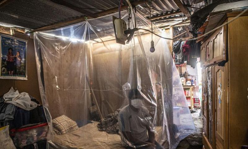 Jonathan, 30, sits on his bed behind a plastic protection as doctors make a round of visits in Ate, on the eastern outskirts of Lima