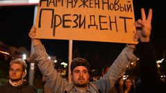 A man holds a poster reading "We need a new president" during a protest rally against police violence