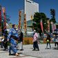 A wrestler walks past a line of people waiting to enter a two-week sumo tournament at Ryogoku Kokugikan, the main sumo arena in Tokyo